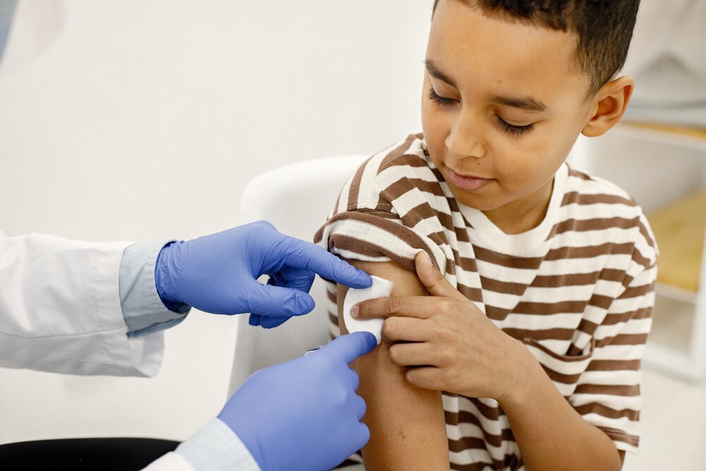 Male doctor holding a cotton on a boy's shoulders after a vaccination